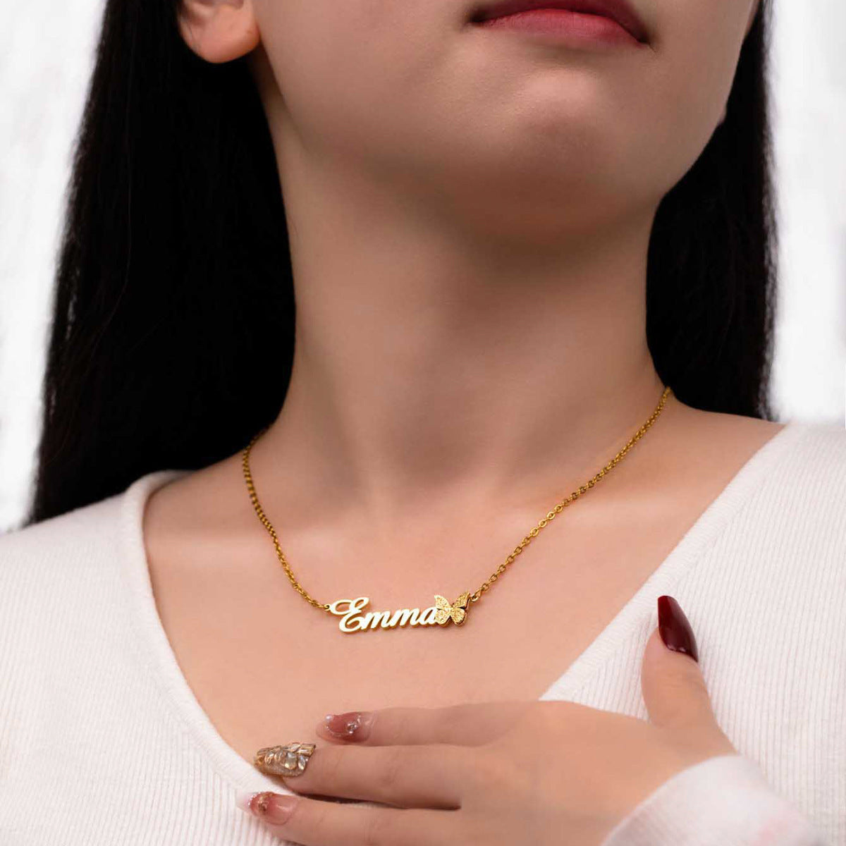 Model wearing gold name necklace with butterfly charm