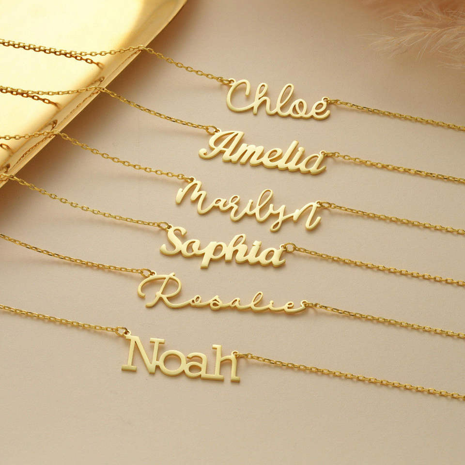 Gold script name necklaces laid flat showing variety