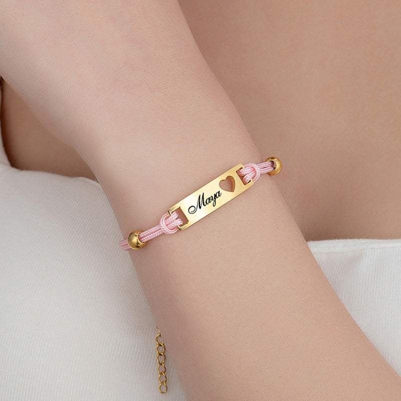 Pink cord bracelet engraved with name, worn on wrist