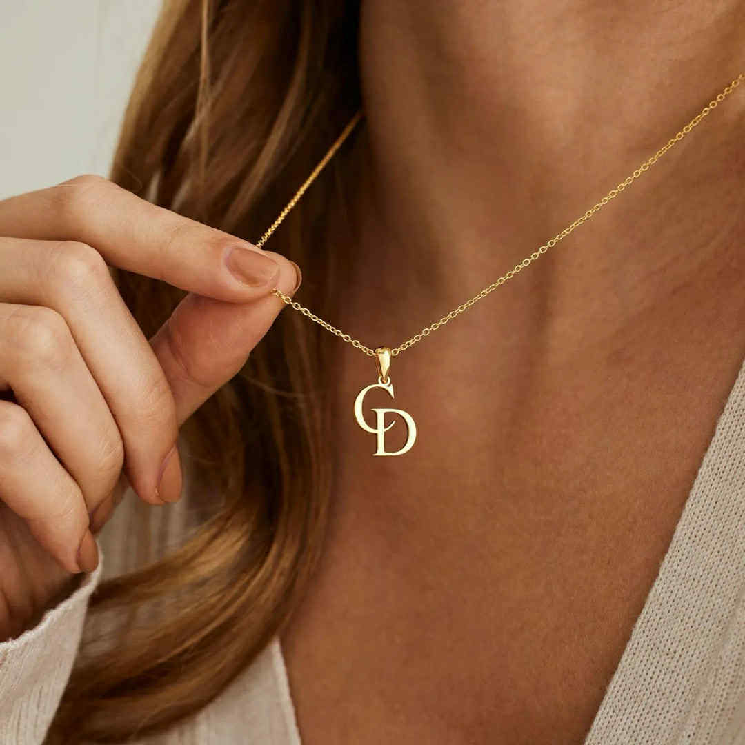 Gold two-letter initial necklace worn on neck