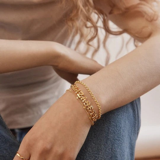 Gold bubble letter name cuff worn on wrist