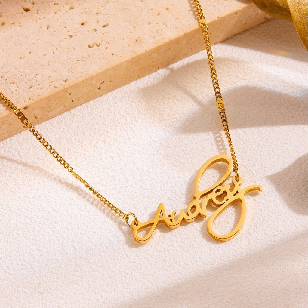 Close-up of gold cursive name necklace