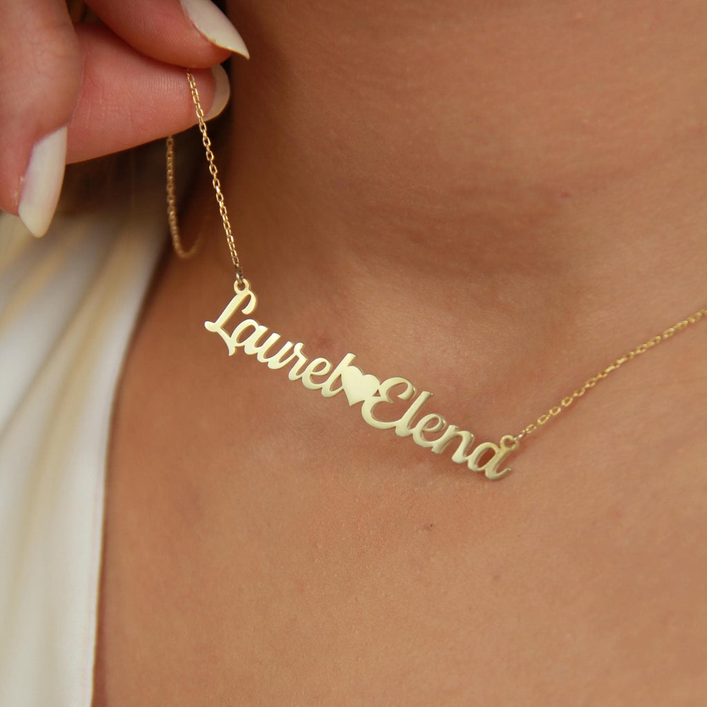 Model wearing gold double-name necklace with heart charm