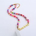 Colorful clay bead necklace with gold nameplate on white background