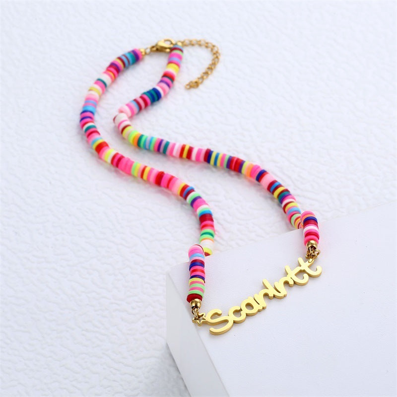 Colorful clay bead necklace with gold nameplate on white background