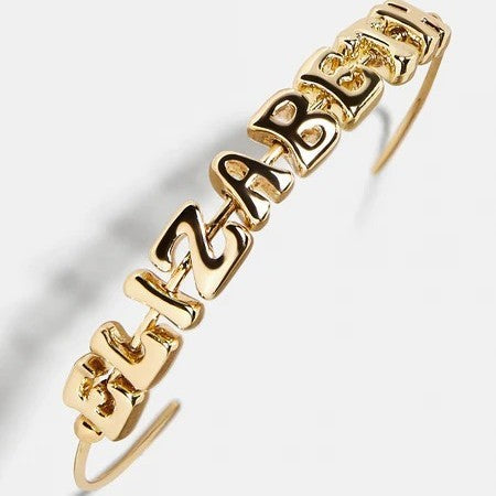 Gold bubble letter cuff bracelet on white background