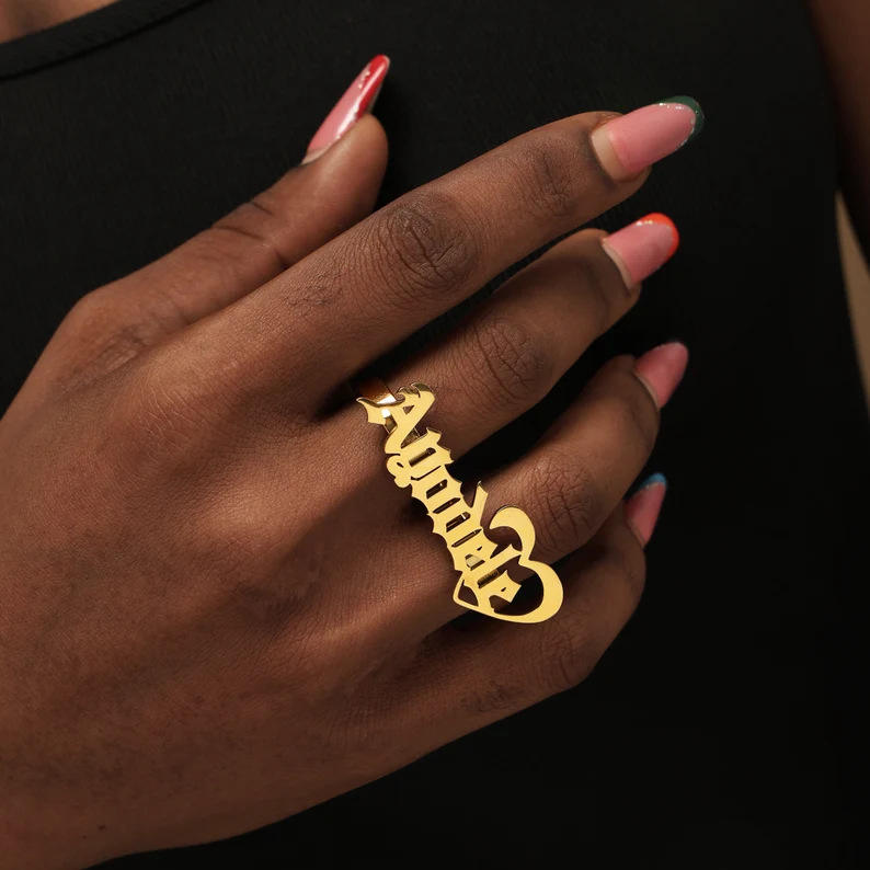 Model's hand wearing gold script name ring