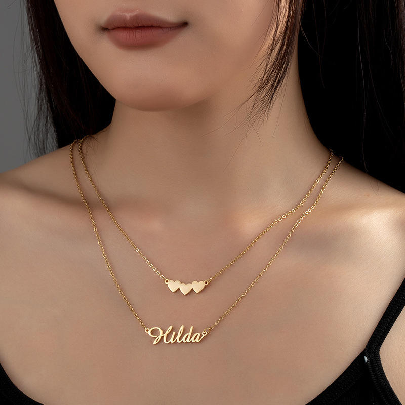 Model wearing gold double-layer necklace with heart charm and name pendant