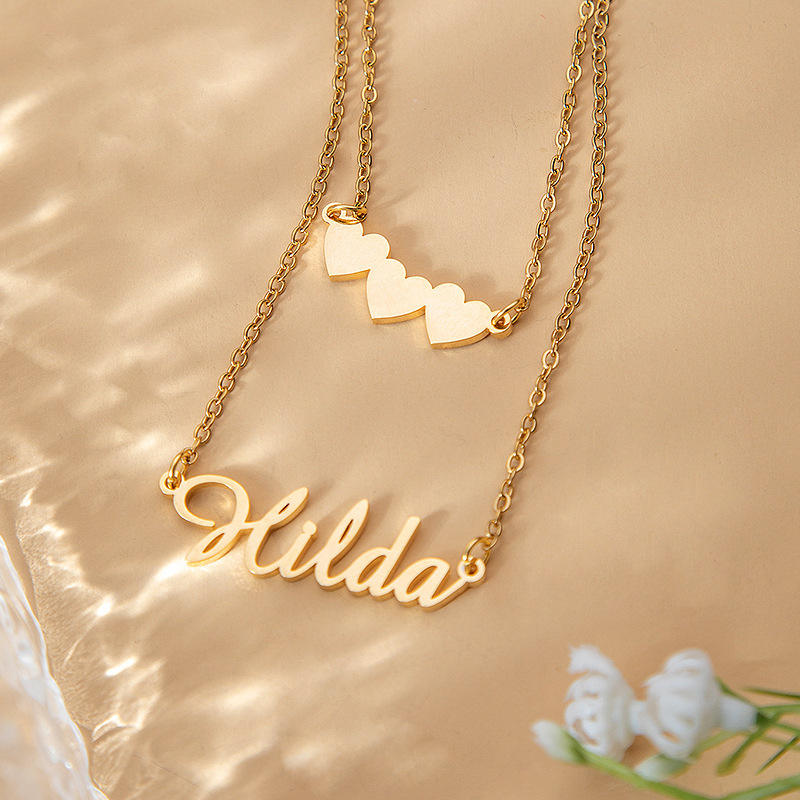 Double-layer gold necklace with heart charm and name pendant flat lay